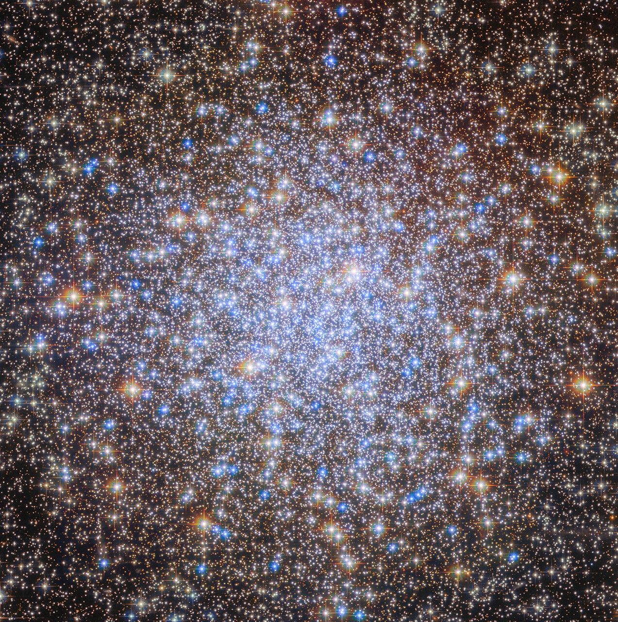 Hubble Space Telescope image of globular cluster NGC 6723 — thousands of stars in orange and blue, tightly packed at the centre and spreading outward like a chandelier