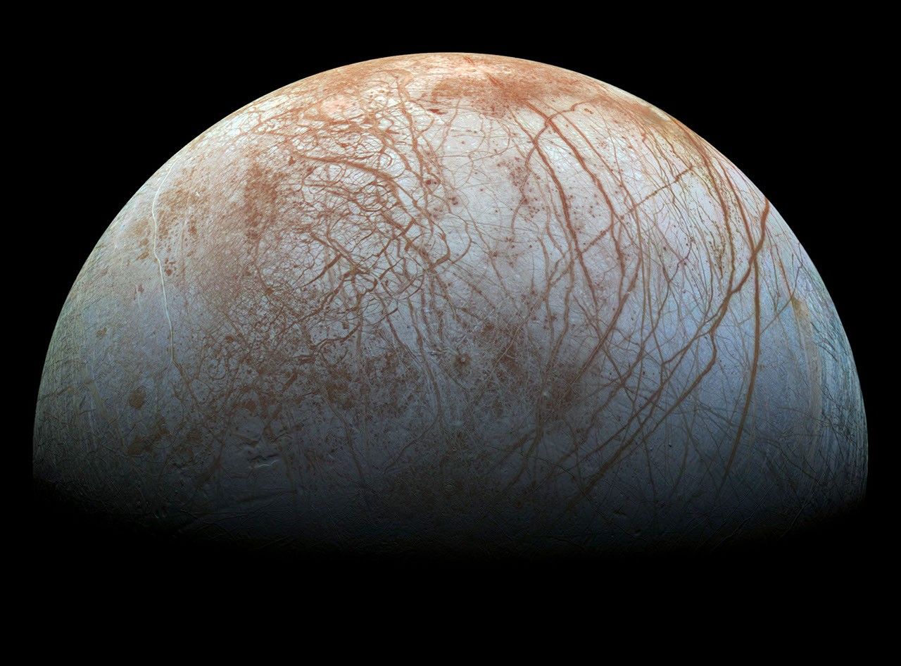 High-resolution close-up of Europa's icy surface showing the intricate network of dark linear cracks and ridges that crisscross the frozen crust