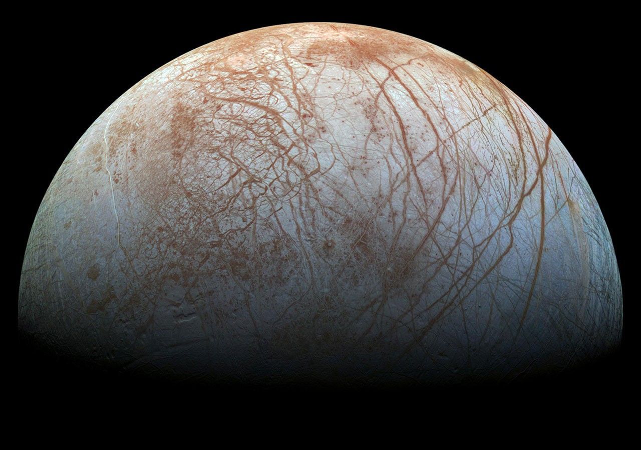 Jupiter's moon Europa — an icy white world with dark linear cracks crisscrossing its smooth frozen surface, photographed by NASA's Galileo spacecraft