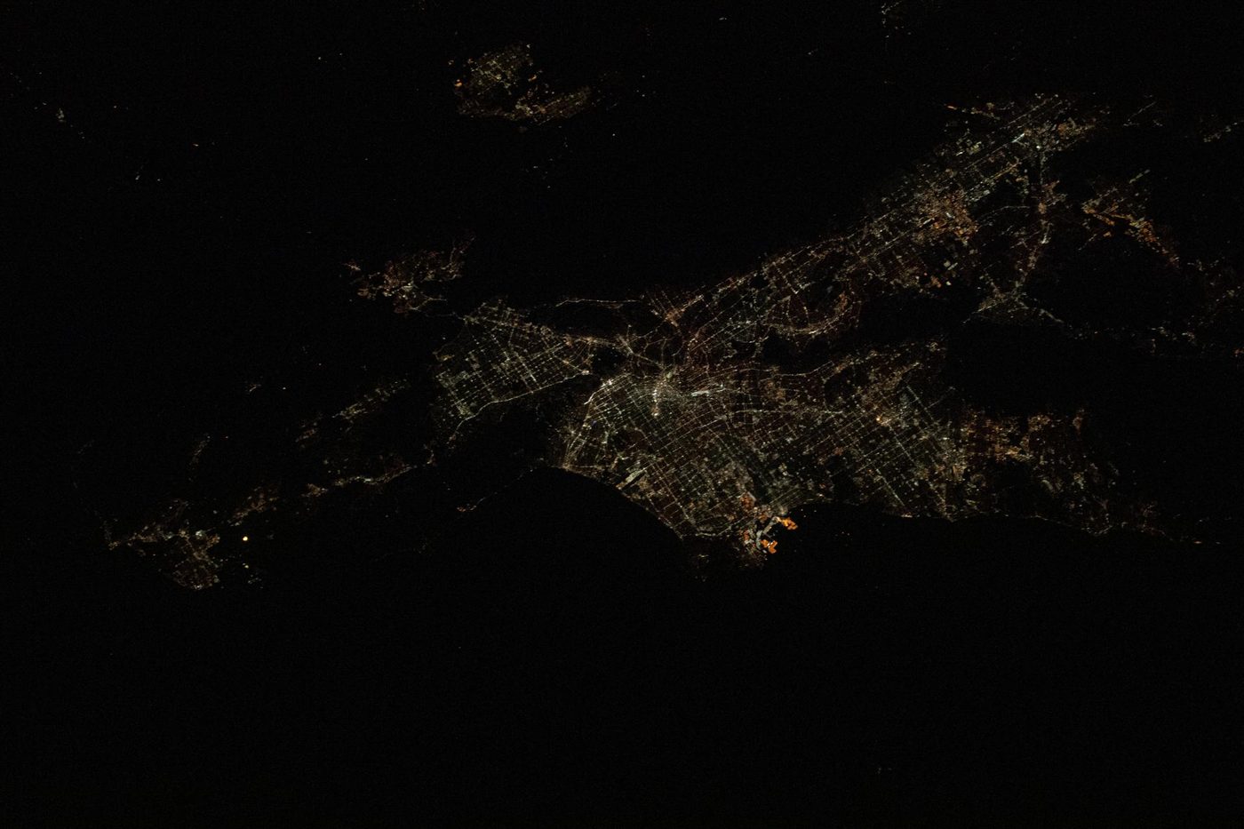 The Los Angeles basin at night from the International Space Station, the city lights filling the plain between the dark mountains and the Pacific