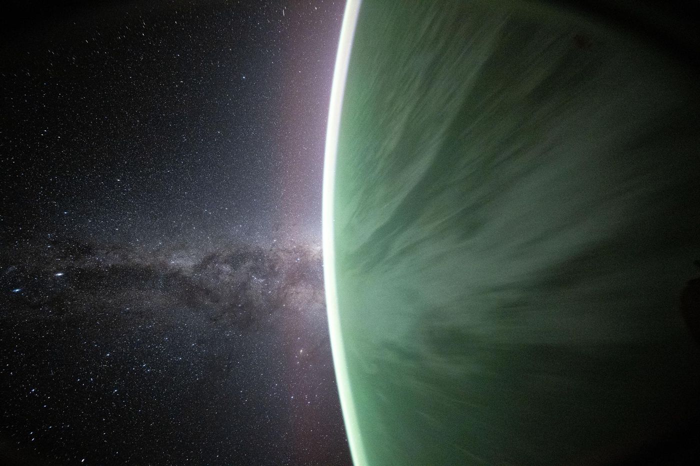 The Milky Way rising beyond the green aurora-lit limb of Earth, photographed from the International Space Station