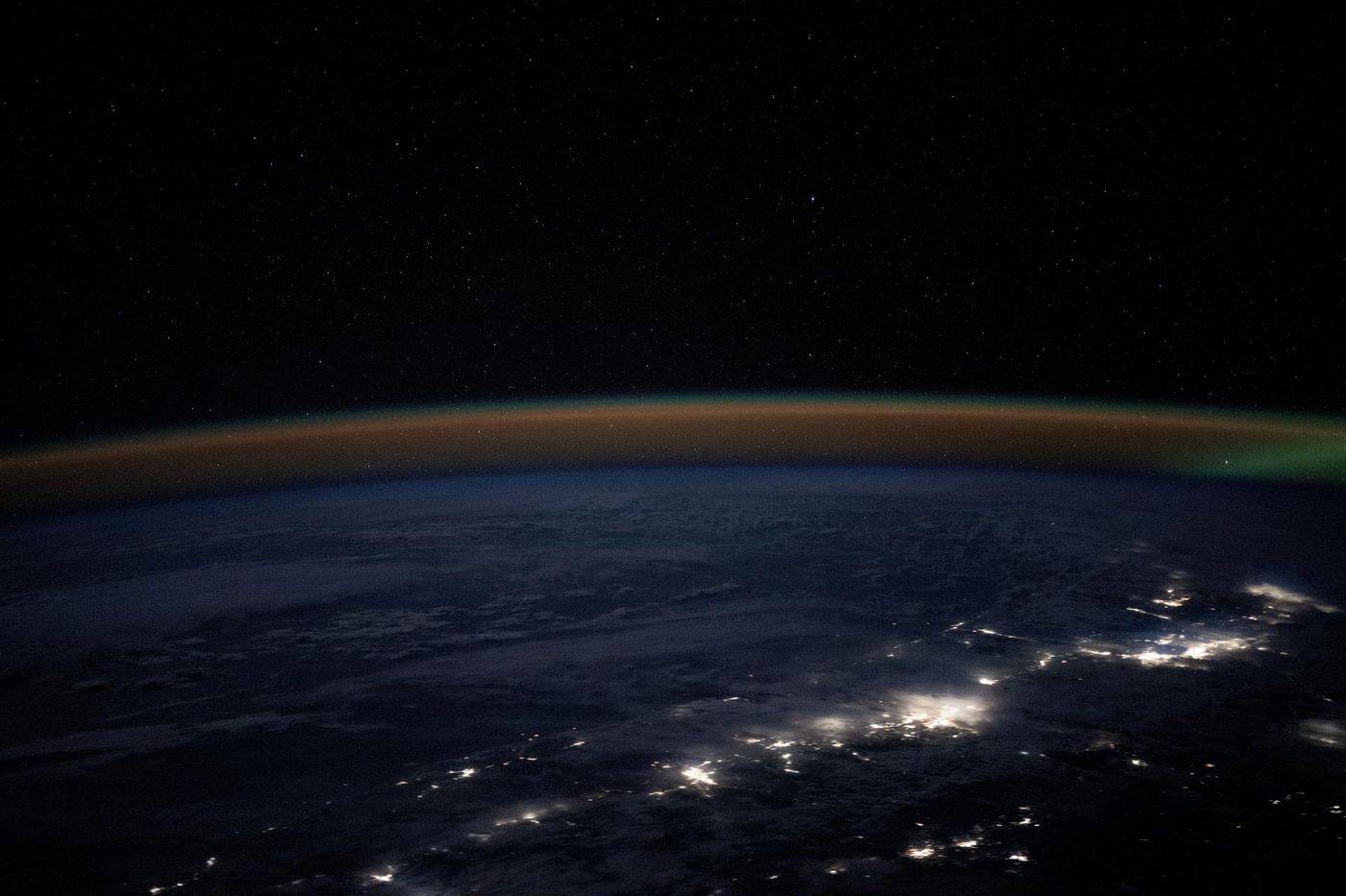 City lights of Portland, Seattle and Vancouver along the dark Pacific Northwest coast at night, under a band of airglow, from the International Space Station