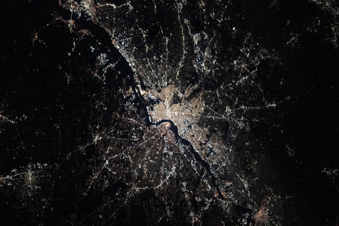 Philadelphia at night from the International Space Station, the gold grid of Center City beside the dark curve of the Delaware River with New Jersey across the water
