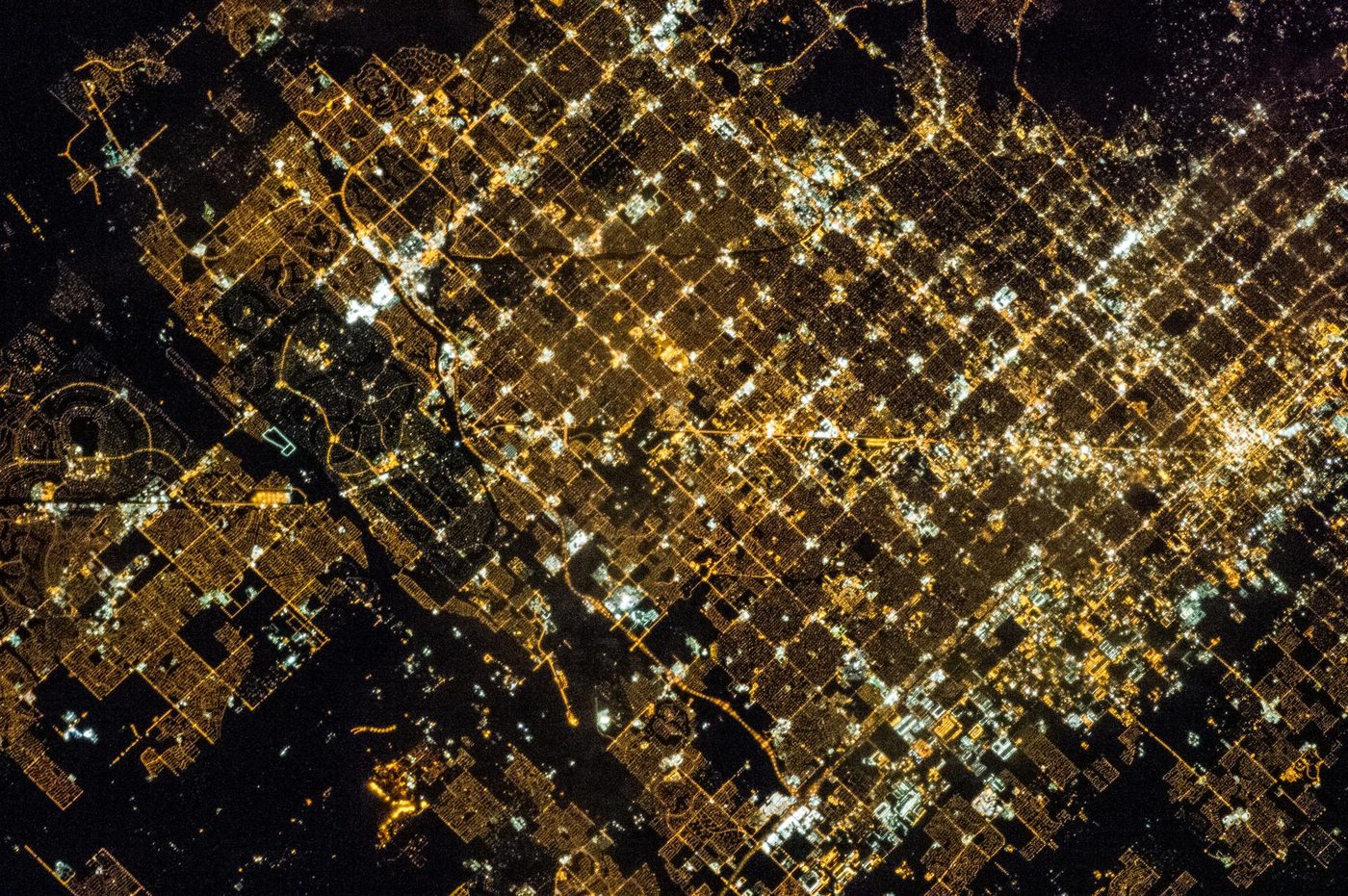 The Phoenix street grid glowing gold at night, photographed from the International Space Station, with dark desert at its edges