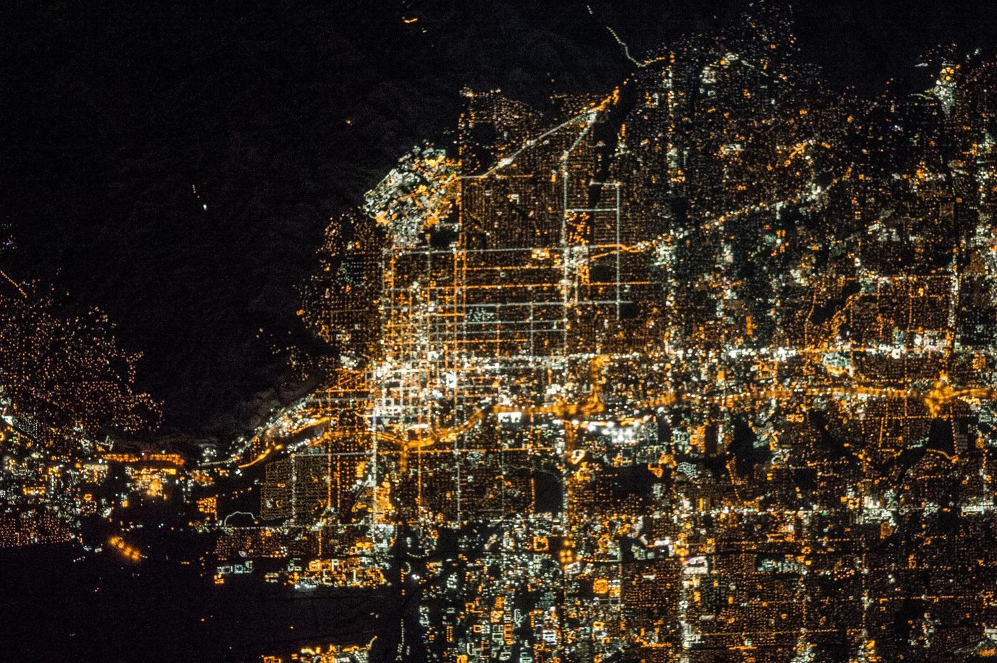 Salt Lake City at night from the International Space Station, its street grid glowing gold against the dark Wasatch Range and the Great Salt Lake
