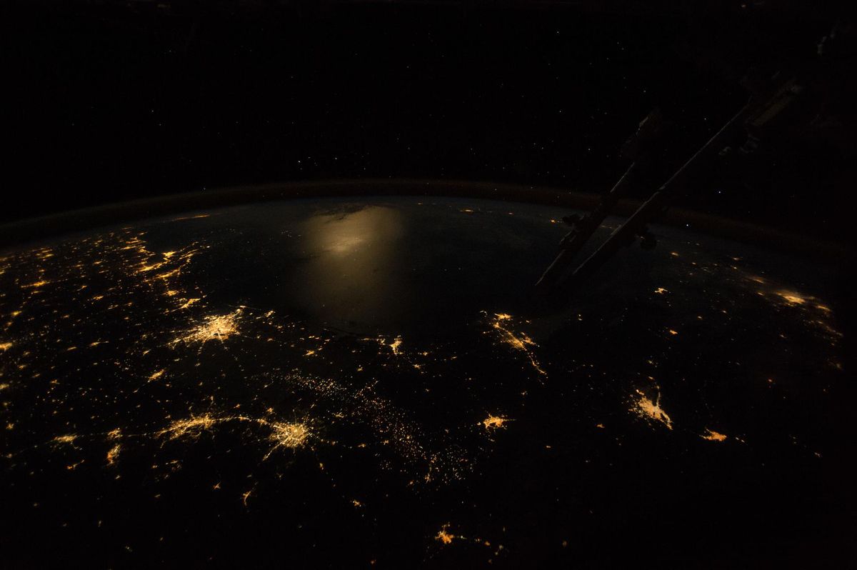 The Texas Gulf Coast at night from the International Space Station, with moonlight reflecting off the dark Gulf of Mexico beyond the city lights