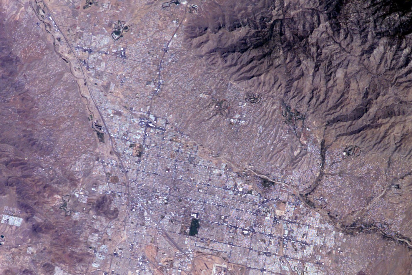 Tucson's mile-square street grid seen from the International Space Station, with the rugged Santa Catalina Mountains rising along the top right