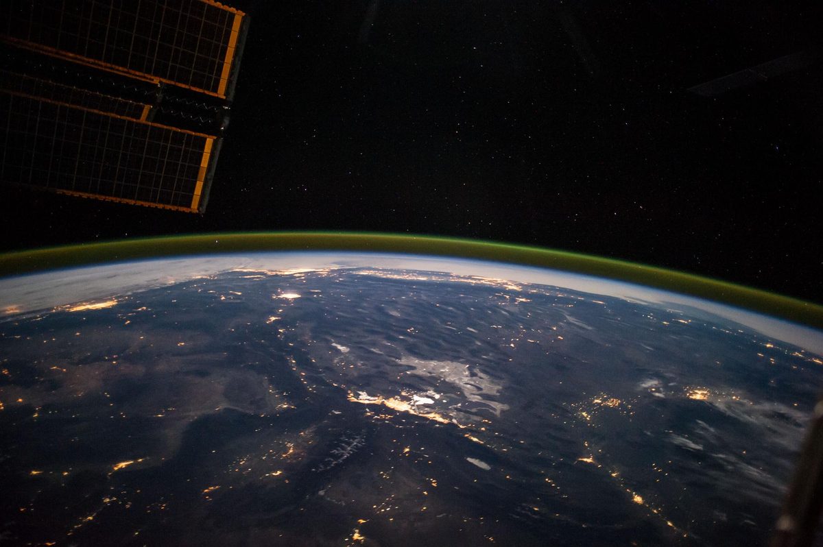 A moonlit panorama of the western United States from the International Space Station, city lights scattered across dark desert and mountains under a green airglow