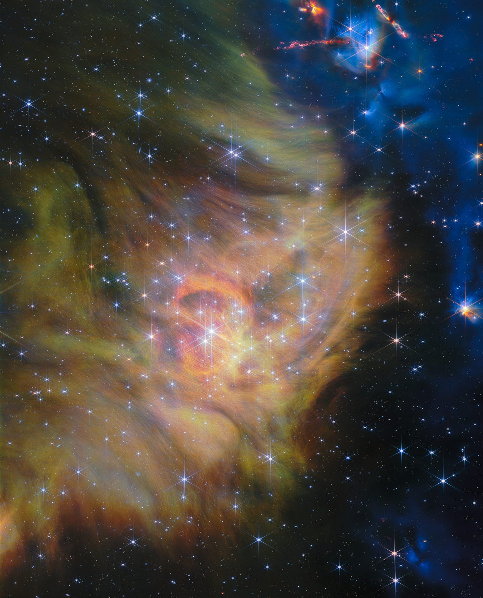 Webb NIRCam image of star-forming region IC 348 — the left two thirds show thick green and yellow clouds of gas and dust, while the right third is black space speckled with stars and galaxies; bright stars crowned with six long diffraction spikes fill the scene, and glowing blue jets shoot from hidden protostars in the upper right