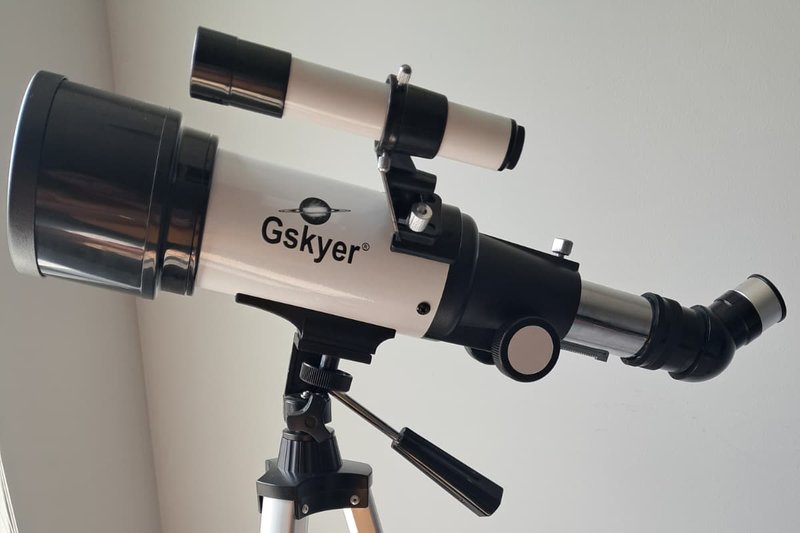 Gskyer 70mm AZ Refractor mounted on its aluminium tripod — showing the plastic alt-azimuth mount head, tripod legs, and slow-motion control cable